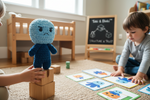 Bloki Handpuppe steht auf Holzbausteinen während Kinder mit Karten spielen und Selbstvertrauen entwickeln