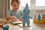 Toki Handpuppe steht auf Karten während ein Kind mit dem Toki & Bloki Kartenspiel spielt
