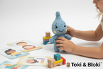 Toki Handpuppe auf hellem Hintergrund mit Kind beim Spielen und Emotionenkarten